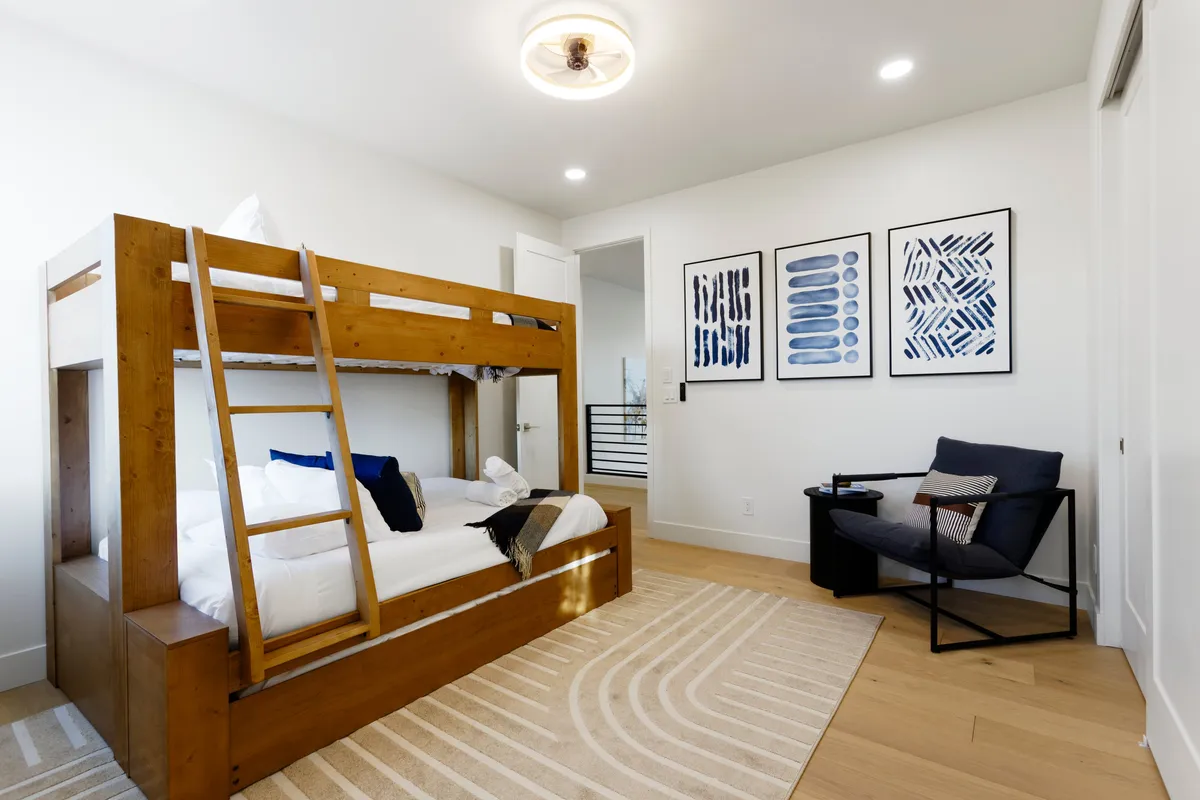 A cheerful bunk suite with a classic bunk bed, playful artwork, and a comfortable armchair. The space is designed to appeal to younger guests, offering both functionality and a sense of fun, with cozy corners for reading or play.