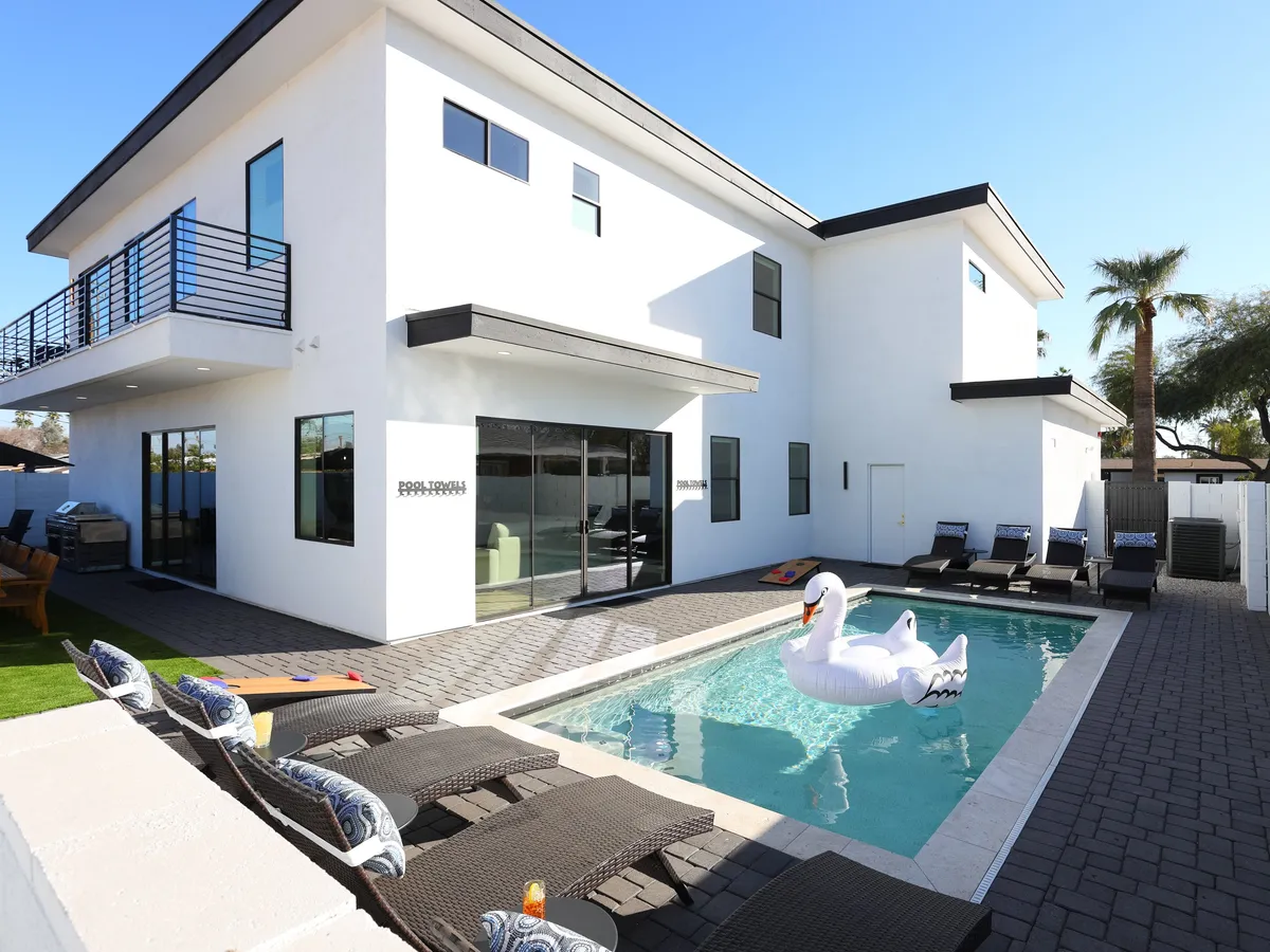 A lively pool scene featuring a large inflatable swan floating on a sparkling pool, with a modern seating area nearby. The setting is bright and cheerful, ideal for swimming, sunbathing, and playful activities, while the surrounding architecture maintains an upscale feel.